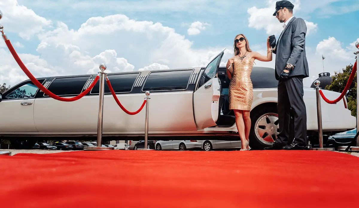 Woman exiting limousine onto red carpet.